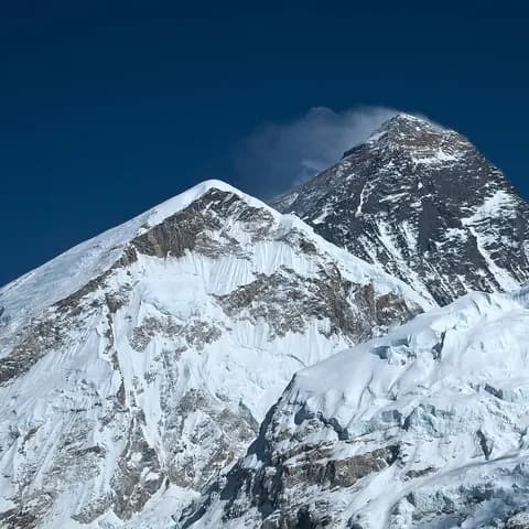 Snow-covered Everest summit under a deep blue morning sky